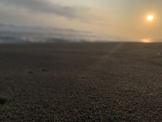 blurry background of beach sand and evening sunset with waves