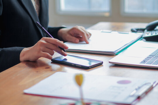 The businesswoman is reviewing the results from the documents prepared to report the earnings at a meeting to the investors about the annual profit. Young businesswoman checking annual results