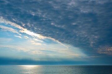Fototapeta premium Sun beams trough the clouds in a cloudy sunset