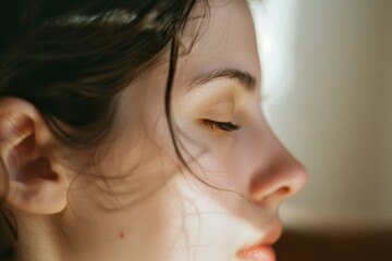 Fototapeta premium A serene portrait of a woman with eyes closed, basking in soft, warm light, capturing a moment of quiet relaxation and introspection.