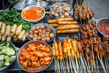 Obraz premium Delve into the vibrant world of Thai street food with skewers, spring rolls, and aromatic sauces tantalizing your taste buds and invigorating your senses.