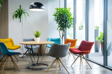Fototapeta premium Modern, vibrant office lounge with colorful chairs, a round table, indoor plants, and large windows offering a bright, inviting atmosphere.