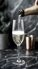 Photo of a bottle being poured into an elegant champagne glass, with the sparkling bubbles visible against grey stone tiles in a minimalist setting