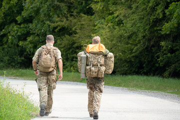 Naklejka premium close-up of two army soldiers tabbing with 40Kg and 25Kg bergens