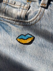 Beaded blue yellow lips brooch over blue denim.