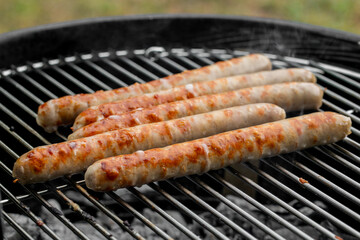 Grilled sausages on a barbecue grill for a summer cookout, ideal for Fourth of July celebrations or weekend gatherings