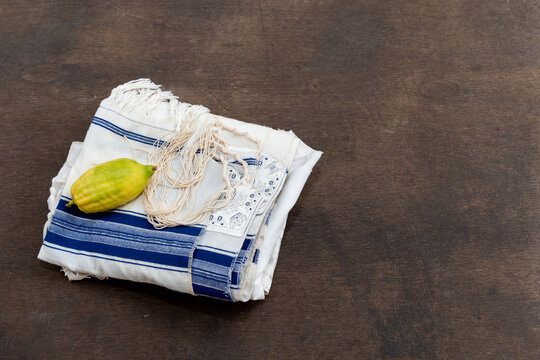 Etrog or citron fruit resting on a blue and white Jewish tallit prayer shawl with tzitzit.
