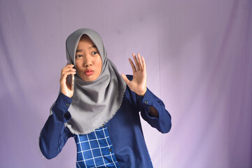 Portrait of a woman calling happily, an Indonesian Muslim woman smiling happily at the camera with a smartphone in her hand