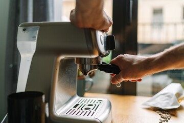 A person preparing coffee using an espresso machine in a cozy kitchen setting.