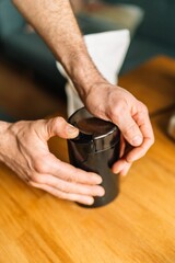 Close-up of male hands using an electric coffee grinder on a wooden table