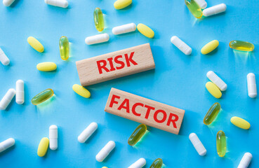 Risk Factor symbol. Concept word Risk Factor on wooden blocks. Beautiful blue background with pills. Medicine and Risk Factor concept. Copy space