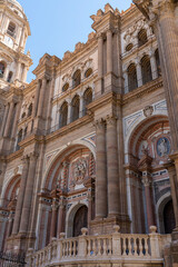 Fototapeta premium A striking view of the intricate facade of Málaga Cathedral, showcasing its grand architecture against a clear blue sky. Ideal for themes of historic landmarks, architecture, and Spanish heritage.