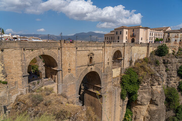  The iconic Puente Nuevo Bridge in Ronda, Spain, gracefully arches over the deep Tajo Gorge, with historic buildings perched on the cliffs. Perfect for themes of architecture, history, and travel.