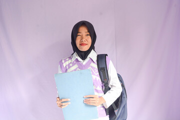 Portrait of smiling professional business woman, happy young asian indonesian female executive or businesswoman holding job registration file standing in office at workplace, looking at copy space.