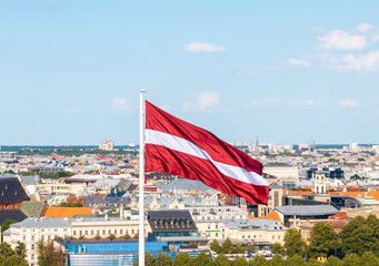 Latvian national flag waving with Riga cityscape in the background