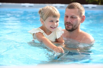 Fototapeta premium Happy father having fun with his daughter in swimming pool