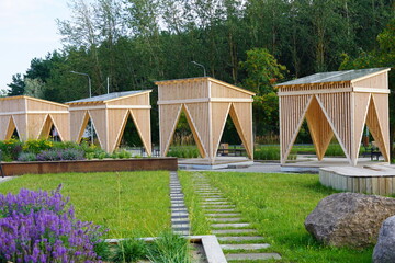 Four modern wooden arbors, gazebo on the back. Landscape design with green grass and grey stones....