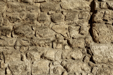 Ancient Stone Wall Texture Featuring Irregular Boulders in Warm, Earthy Tones Illuminated by Natural Light