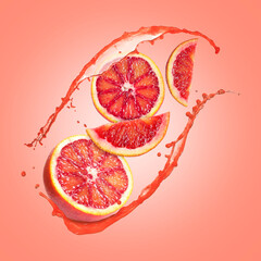 Juice splashes and fresh red oranges in air on coral color background