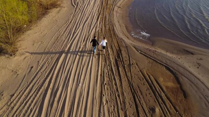 A Loving Couple run Hand in Hand on a Beautiful Sandy Beach During a Breathtaking Sunset