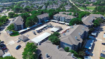 Complex of apartment buildings along Ascension Boulevard in North Arlington, Texas with modern covered parking and garage, multistory townhomes condos rental community, sunny weather, aerial view