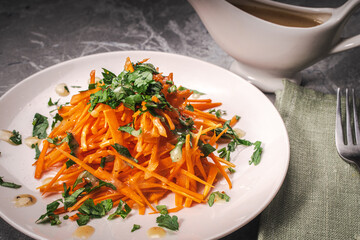 Carrot and parsley salad with Vinaigrette sauce on a white plate on a gray background. A place to copy the space.