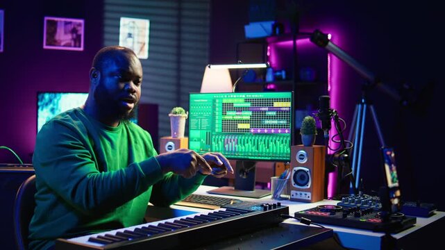 Musician doing online paid classes to help people play piano notes, teaching lessons from his home studio and recording video tutorials. Musical instructor playing midi controller keyboard. Camera B.