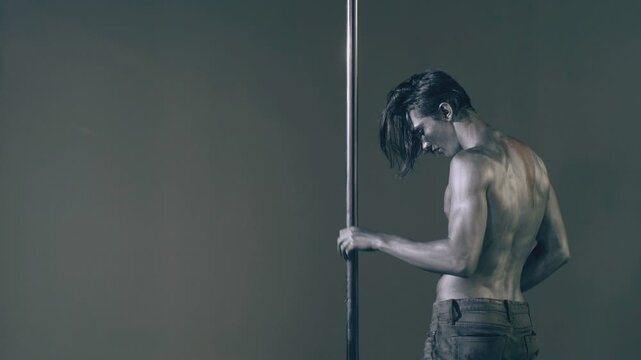 Sexy body of young man. Pole dancer. Sexy man exercise pole dance. Fit slim sexy man performs sensual pole dance. Go-go dancer. Strip dancer. Male athlete doing acrobatic trick on pylon.