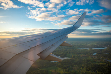 Aircraft flying in sunset. Clouds, rainbow and a wing of airbus from the airplane window