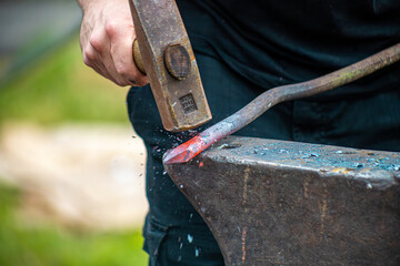A blacksmith hammering a glowing piece of metal on an anvil.