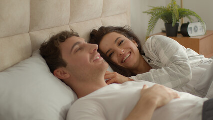 Happy couple man woman lying on bed bedroom female male girl guy laughing smile fun conversation communication joy rest relaxation enjoying together beloved relationship comfortable positive dreamy