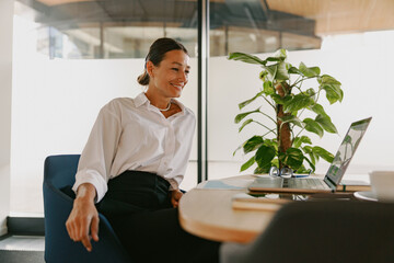A Professional Woman is in a Modern Workspace while Actively Engaged in an Online Meeting