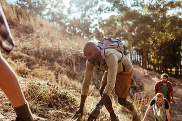 Man climbing steep trail during outdoor hike with friends