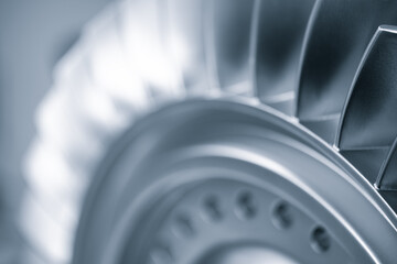 A close up of a turbine blade with a silver color. Concept of precision and engineering, as the blade is a crucial component of a turbine. The focus on the blade highlights its intricate design