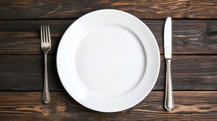 A white plate with a fork and knife on a wooden table