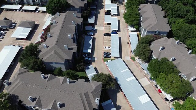 Covered parking structure in large apartment complex near suburban park lush green tree in North Arlington, Texas, multistory rental townhomes condos suburbs Dallas Forth Worth metroplex, flyover