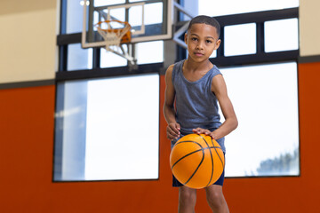 Dribbling basketball, boy practicing in school gym, focusing on skills