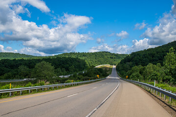 A rural highway in the woods in Franklin, Pennsylvania, USA on a sunny spring day
