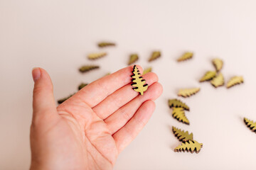 A hand holding small decorative wooden pieces shaped like leaves, perfect for craft projects