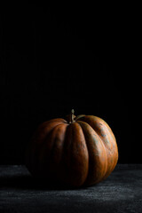 Fresh pumpkin on a dark background. Textured orange pumpkin. Autumn harvest. Ingredient for pumpkin pie.