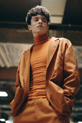 Stylish young man in an orange turtleneck and suit in an urban setting