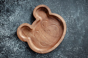 A plate for children in the shape of a bear is made of wood for serving snacks, fruits, nuts,...