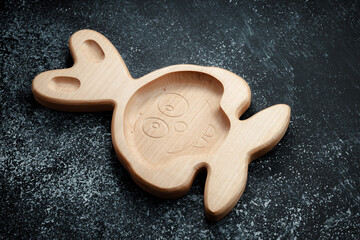 A plate for children in the shape of a bunny is made of wood for serving snacks, fruits, nuts,...