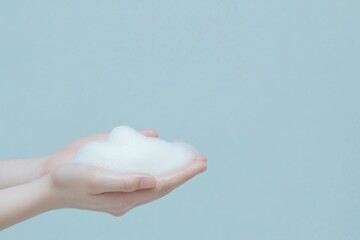 A close-up of hands holding a fluffy bubble of soap against a light blue background, symbolizing cleanliness and freshness.