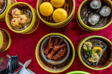 Looking down at dim sum in steamer baskets on a table at a restaurant   in George Town, Penang, Malaysia.
