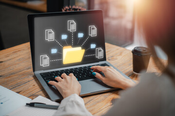 A professional working on a laptop displaying a digital folder and file icons, representing an...