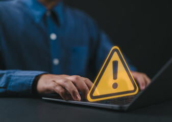 User or developer working on laptop computer with triangle caution warning sign for notification error and maintenance concept, computer virus detected, personal data protection, network security.