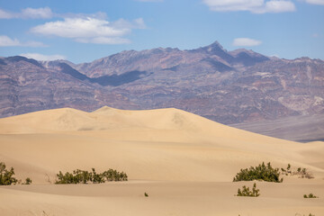 Sand dunes against the backdrop of mountains and sky in Death Valley, California