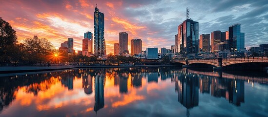 Fototapeta premium skyscrapers reflecting in calm water of river near bridge against cloudy sunset sky