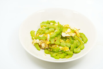 Close up food image of stir-fried bitter melon with chicken egg and oyster sauce in an off - white dish on white background, Asian healthy food menu.